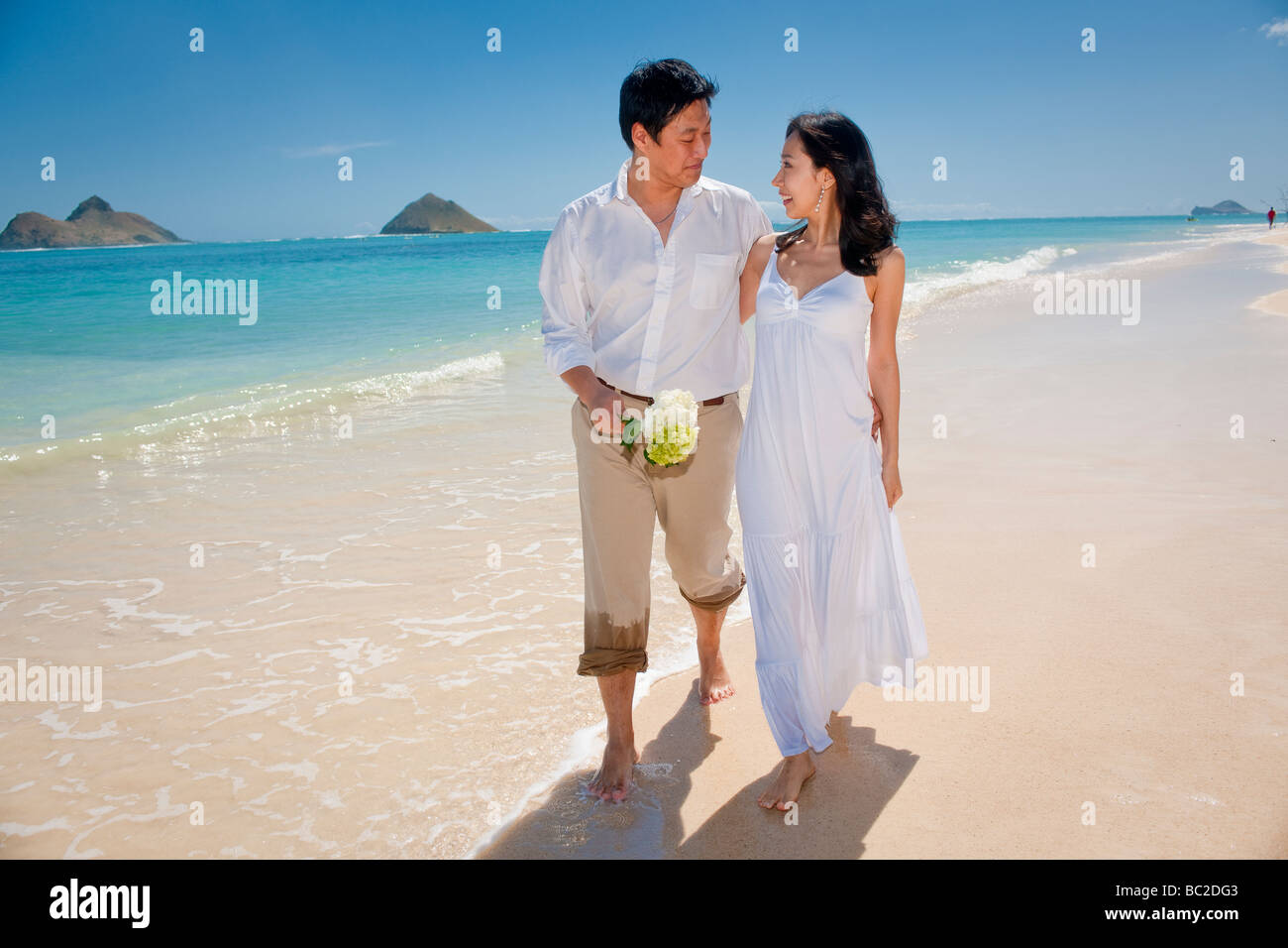 Asiatische Braut und Bräutigam spazieren Sie am Strand von Lanikai als