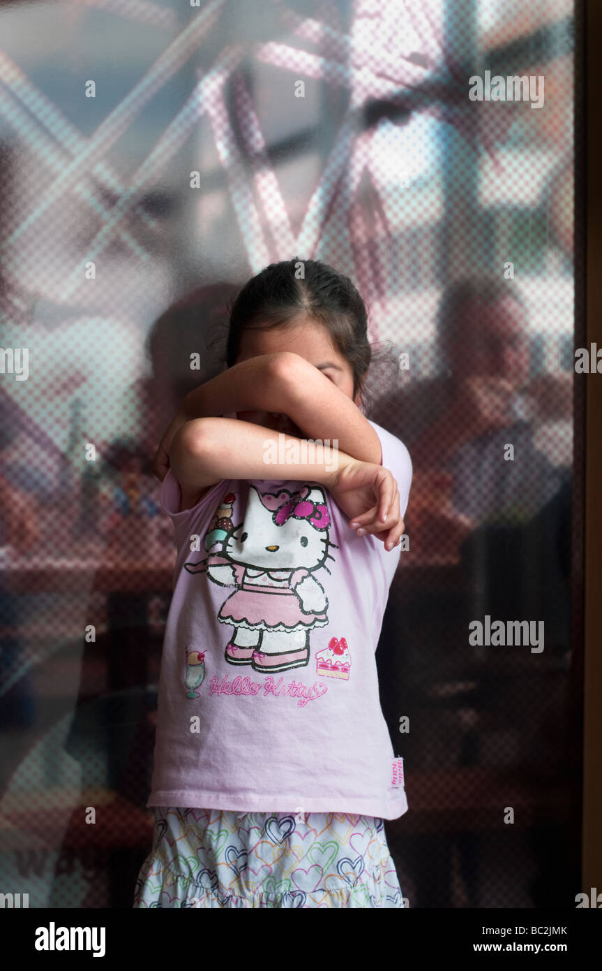 Mädchen 7 Jahre alt verbirgt ihr Gesicht Stockfoto