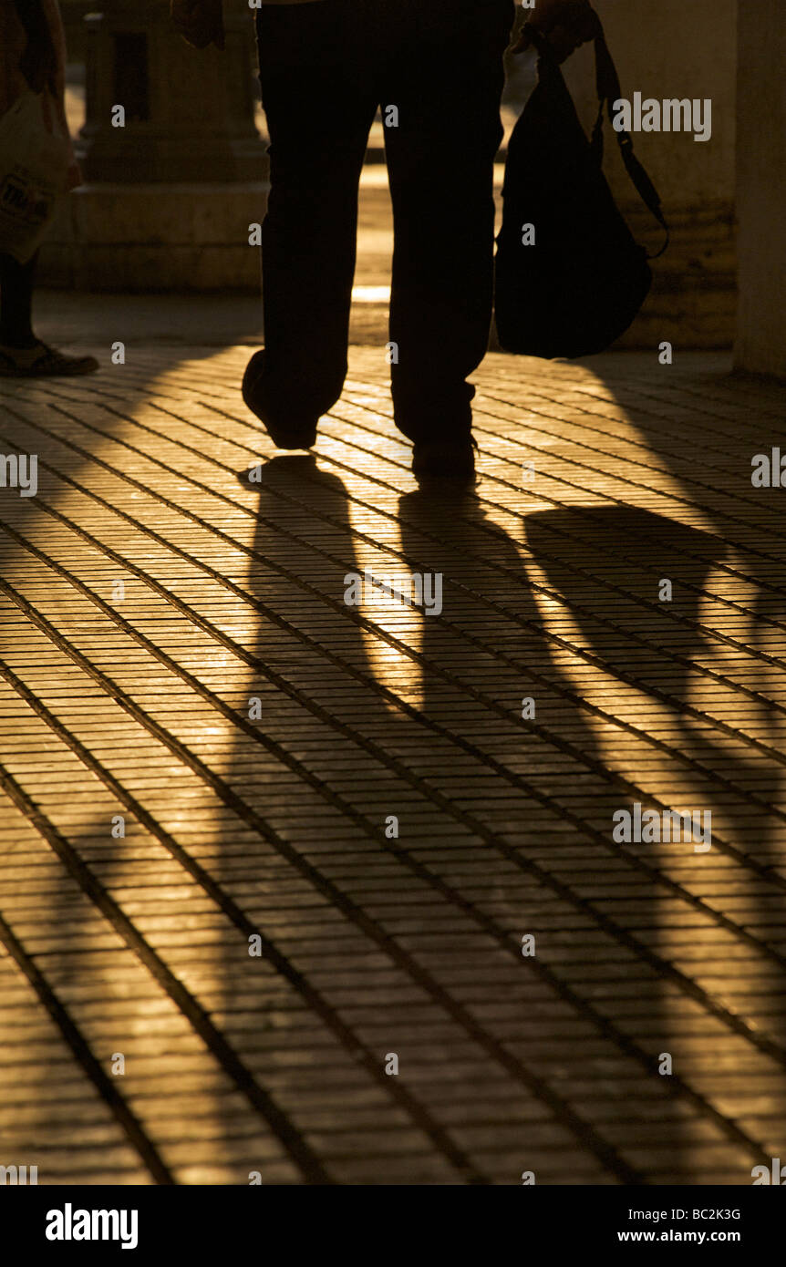 Füße und Beine der Fußgängerzone Silhoutted gegen goldene Sonnenlicht mit Schatten. Stockfoto