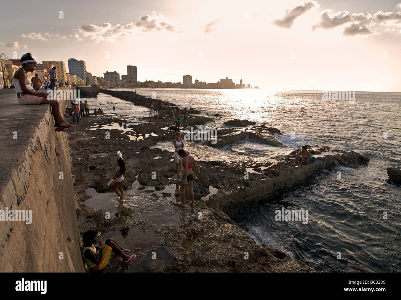 Kubaner genießen die Sonne und das Meer von den Felsen neben dem Malecon bei Sonnenuntergang, Havanna, Kuba Stockfoto