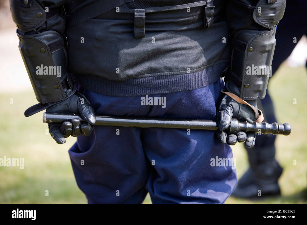 Gendarm (Polizist) mit einem Schlagstock in den Händen von hinten gesehen Stockfoto