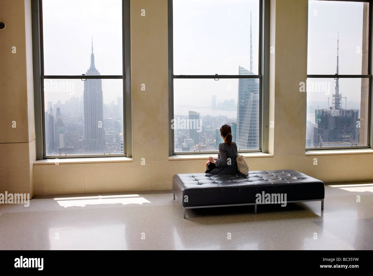 Eine Frau sitzt an der Spitze des Rockefeller Center in New York Blick auf das Empire State Building Stockfoto