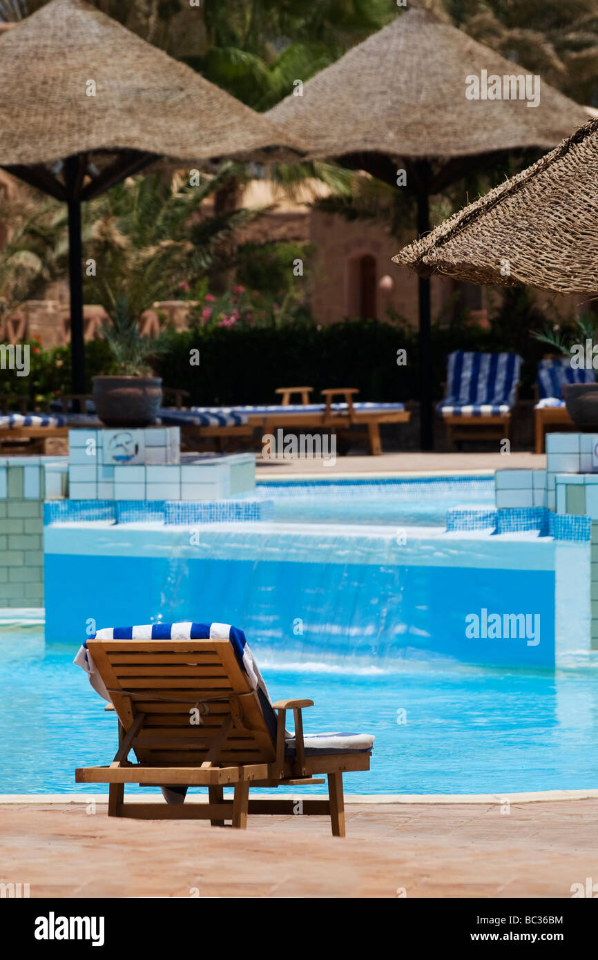 Eine hölzerne Sonnenliege neben einem Schwimmbad in einer Luxus-Ferienanlage Stockfoto