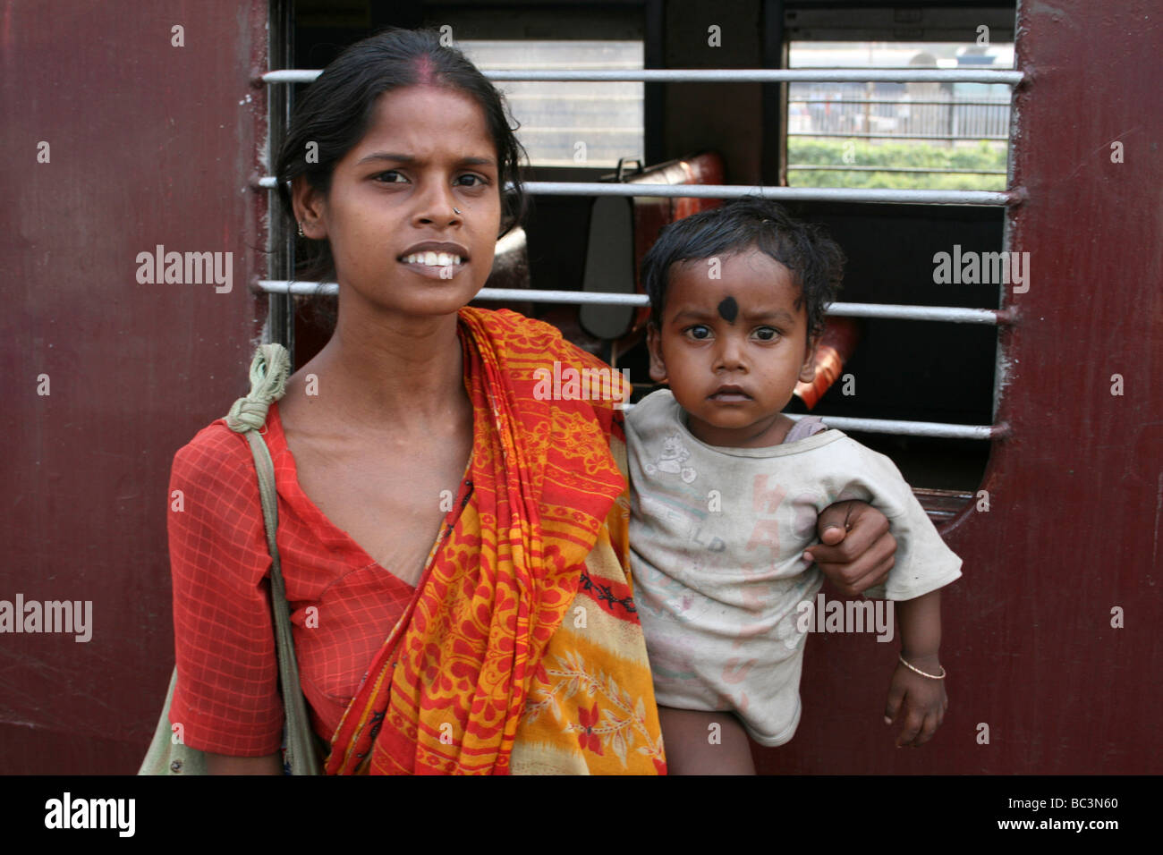 Junge indische Mutter und Baby neben dem Zug In Kolkata, Indien Stockfoto