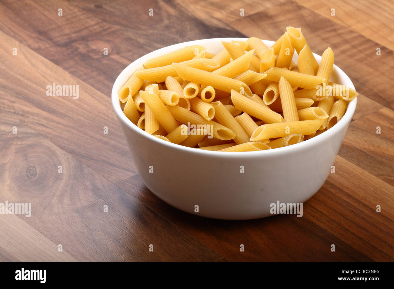 Penne Rigate in weiße Keramikschale auf Holzboden zu trocknen Stockfoto