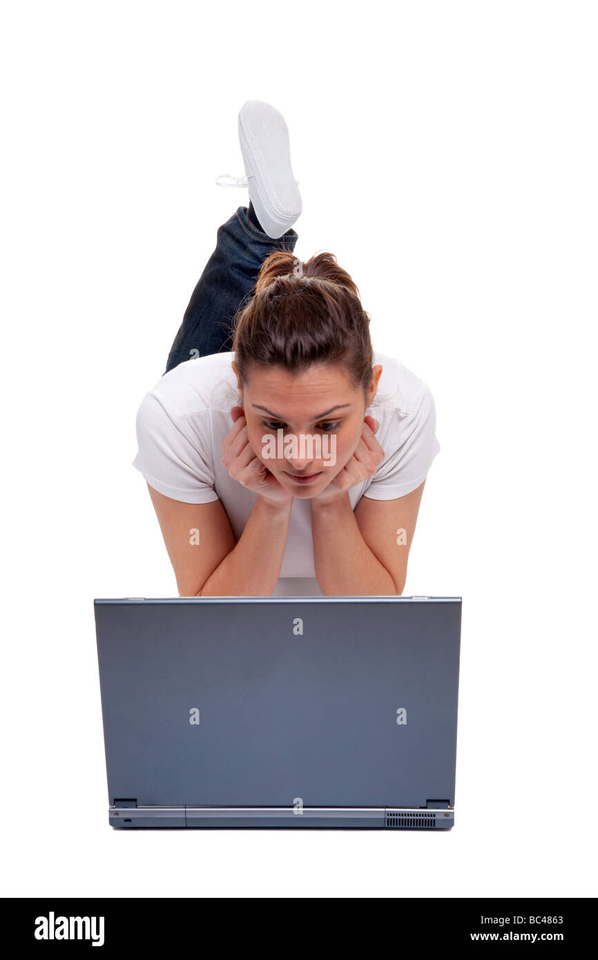 Junge Frau in Freizeitkleidung liegen auf den Bauch auf den Bildschirm eines Laptop-Computers isoliert auf weißem Hintergrund Stockfoto