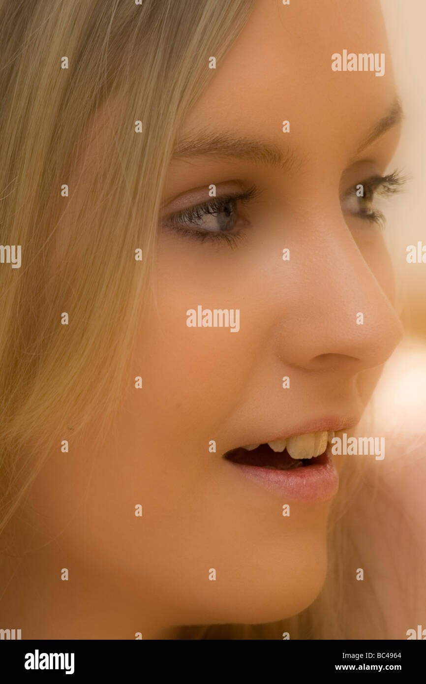 Nahaufnahme, Seitenansicht des Gesichts der schönen blonden Teenager-Frau, 16 - 18 Jahre alt, mit blauen Augen, offenem Mund, reden. Weichfokus. Stockfoto