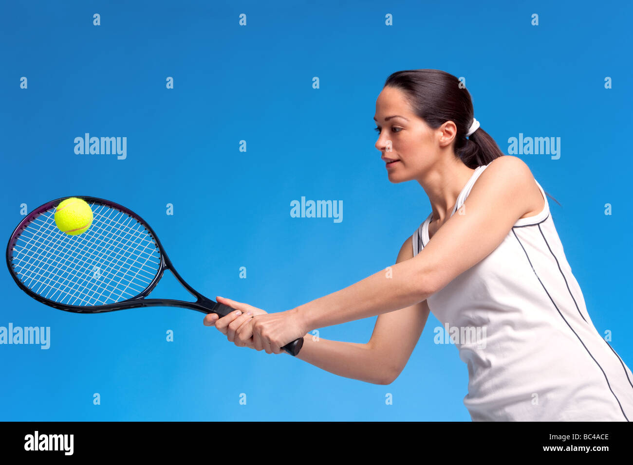 Eine Brünette Frau Tennisspielen auf blauem Grund Stockfoto