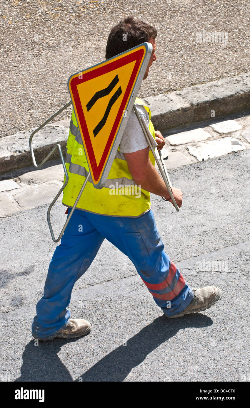Straßenarbeiten Auftragnehmer tragen "Road Narrows" Sicherheit Warndreieck über Schulter - Frankreich. Stockfoto