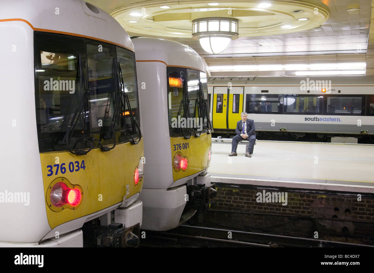 Ein Pendler sitzt wartet auf einen Zug, der Bahnhof Charing Cross, London UK Stockfoto