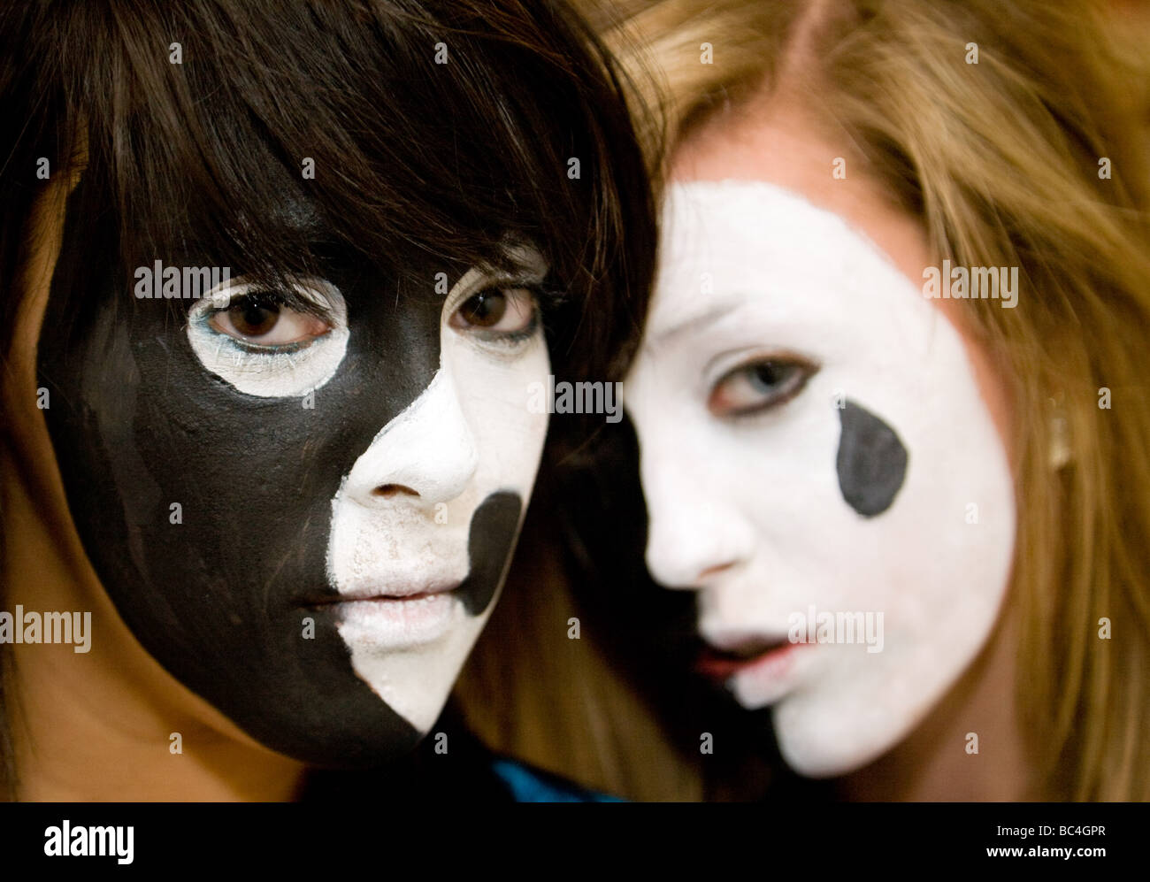 Zwei Mädchen im Teenageralter hatte ihre Gesichter in dramatischen Farben schwarz und weiß lackiert Stockfoto
