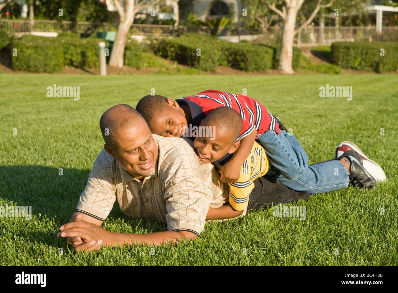 Kalifornien Vati jungen Afrikaner - Eltern und Kinder wrestling genießen und Piling auf tumbling Miteinander außerhalb. Herr © Myrleen Pearson Stockfoto