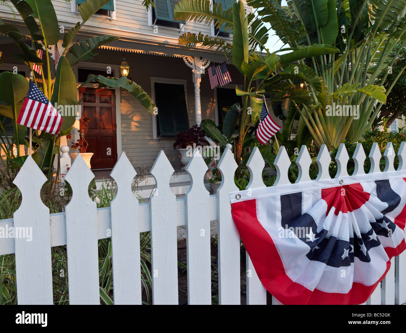 Lattenzaun vor Haus mit US-Fahnen und Girlanden Stockfoto