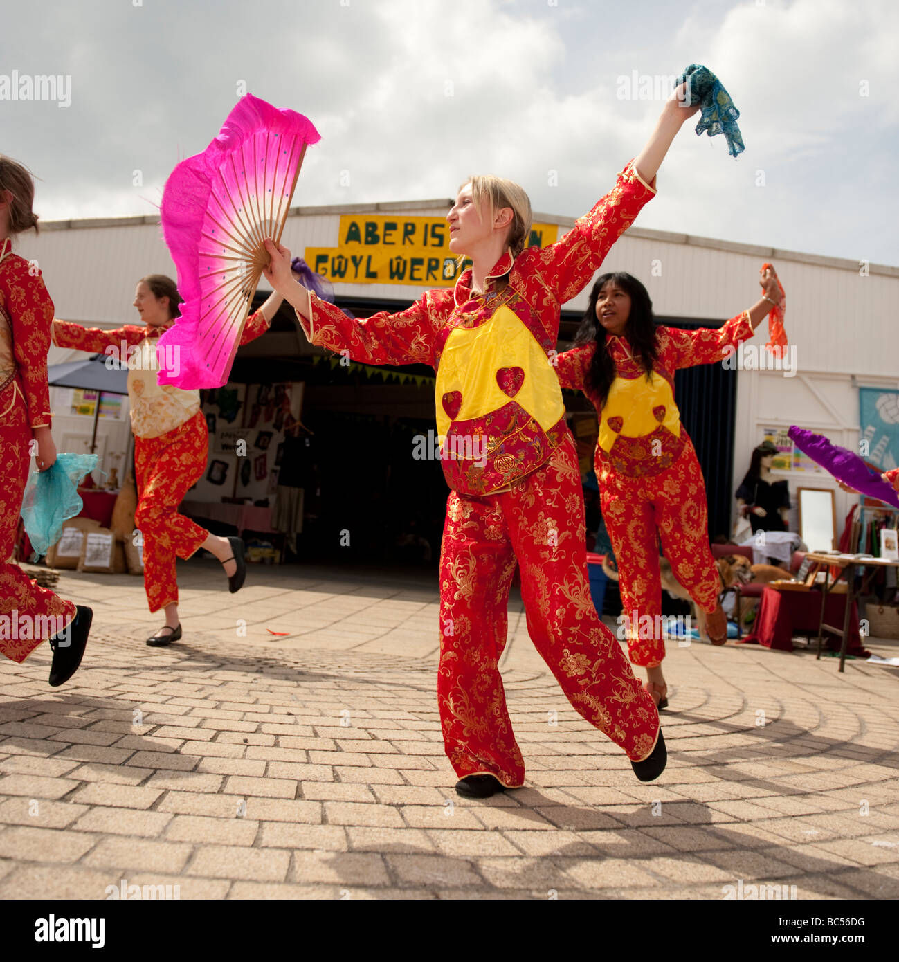 Frauen tragen rote Kleidung winken Fans und Seidenschals, die Durchführung von chinesischen Tanz auf Aberystwyth promenade Wales UK Stockfoto