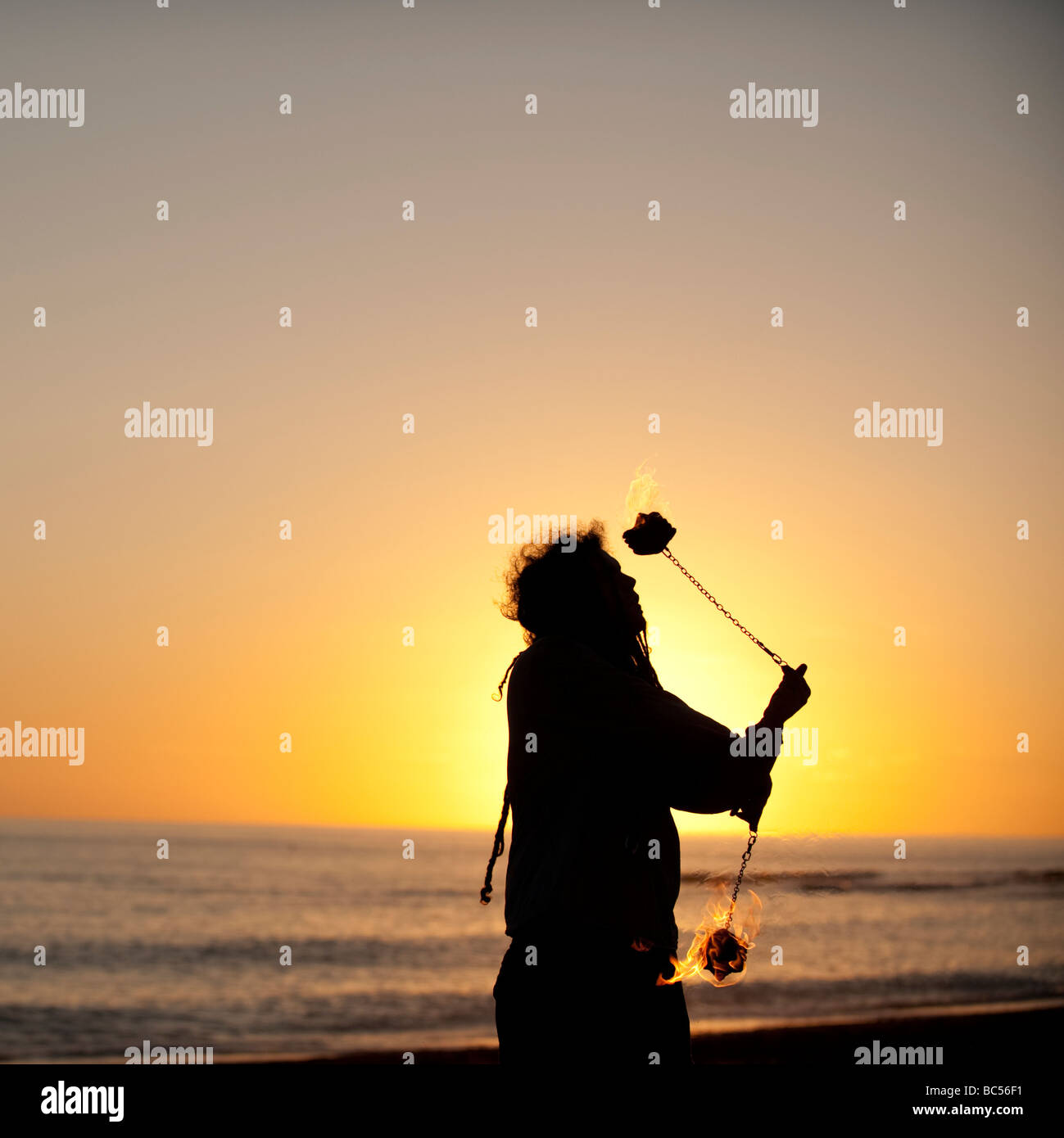 Mann, Jonglieren mit brennenden Poi bei Sonnenuntergang Stockfoto