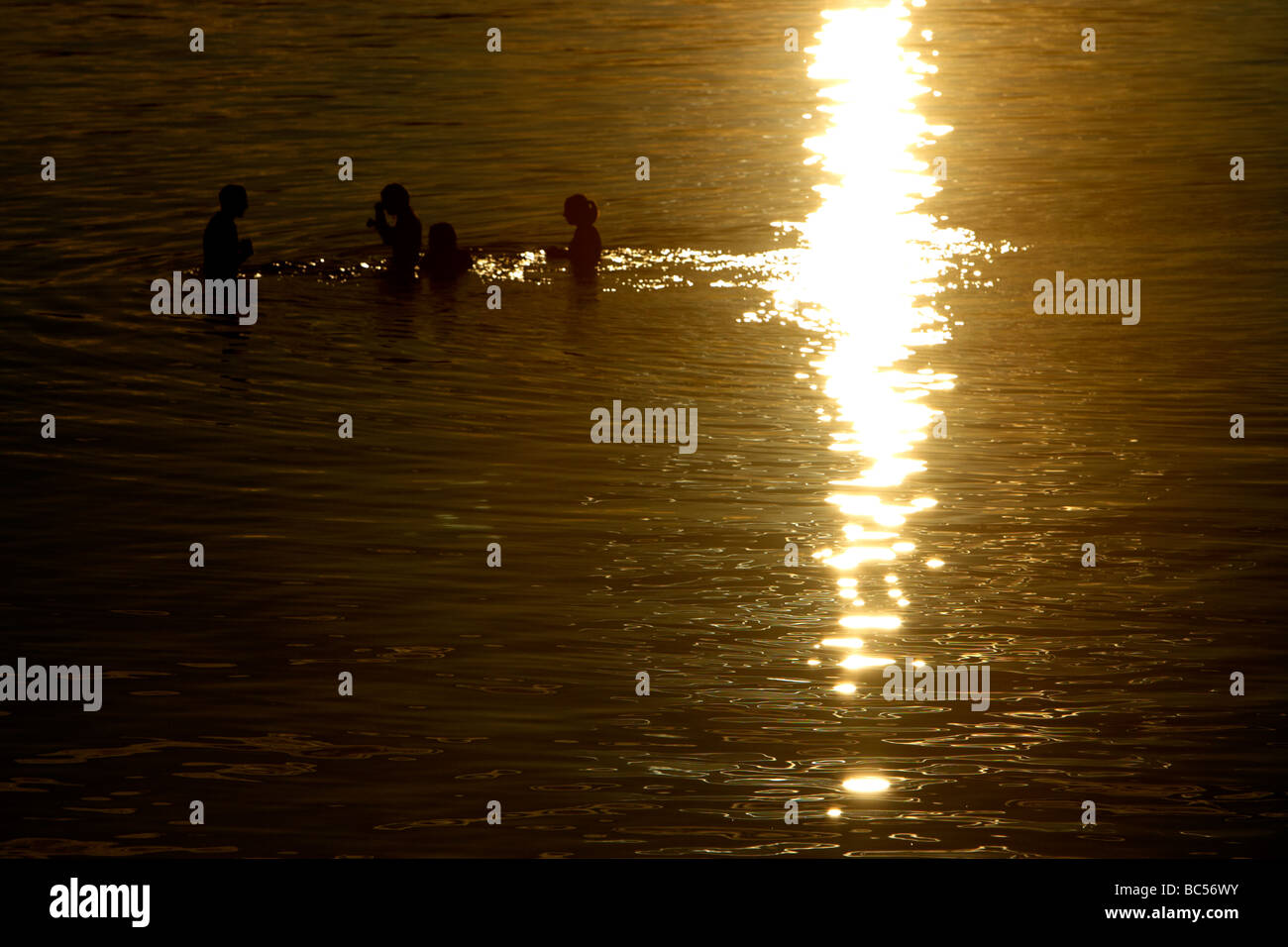 vier junge Leute genießen Sie ein Bad im Meer in der Einstellung Sonnenlicht in Irland Stockfoto