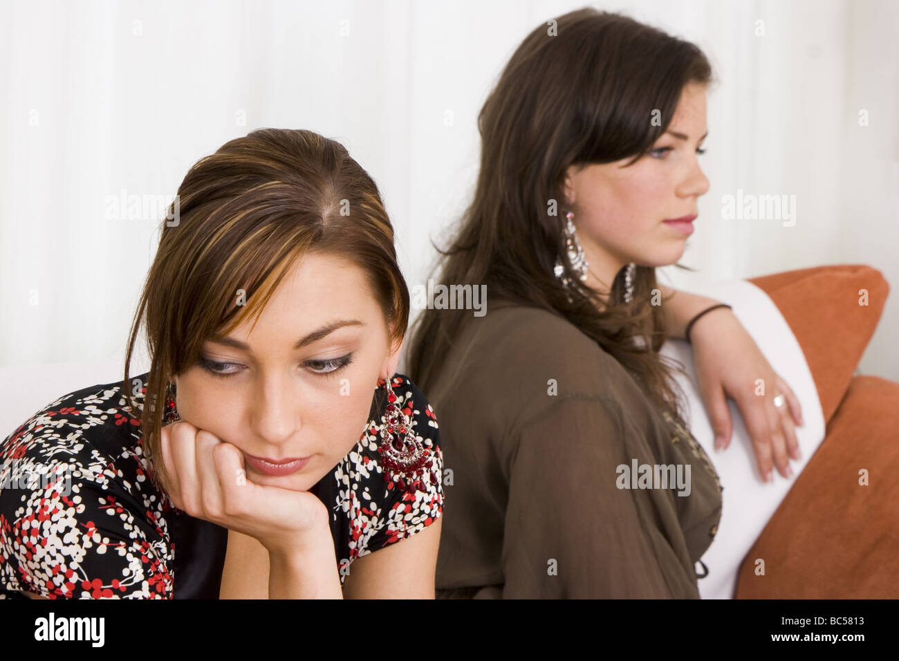 Zwei Mädchen im Teenageralter sitzen still auf Sofa, Rücken an Rücken, wütend gekreuzt und eigensinnig mit einander, durch Zwietracht.   SerieCVS317019 Stockfoto