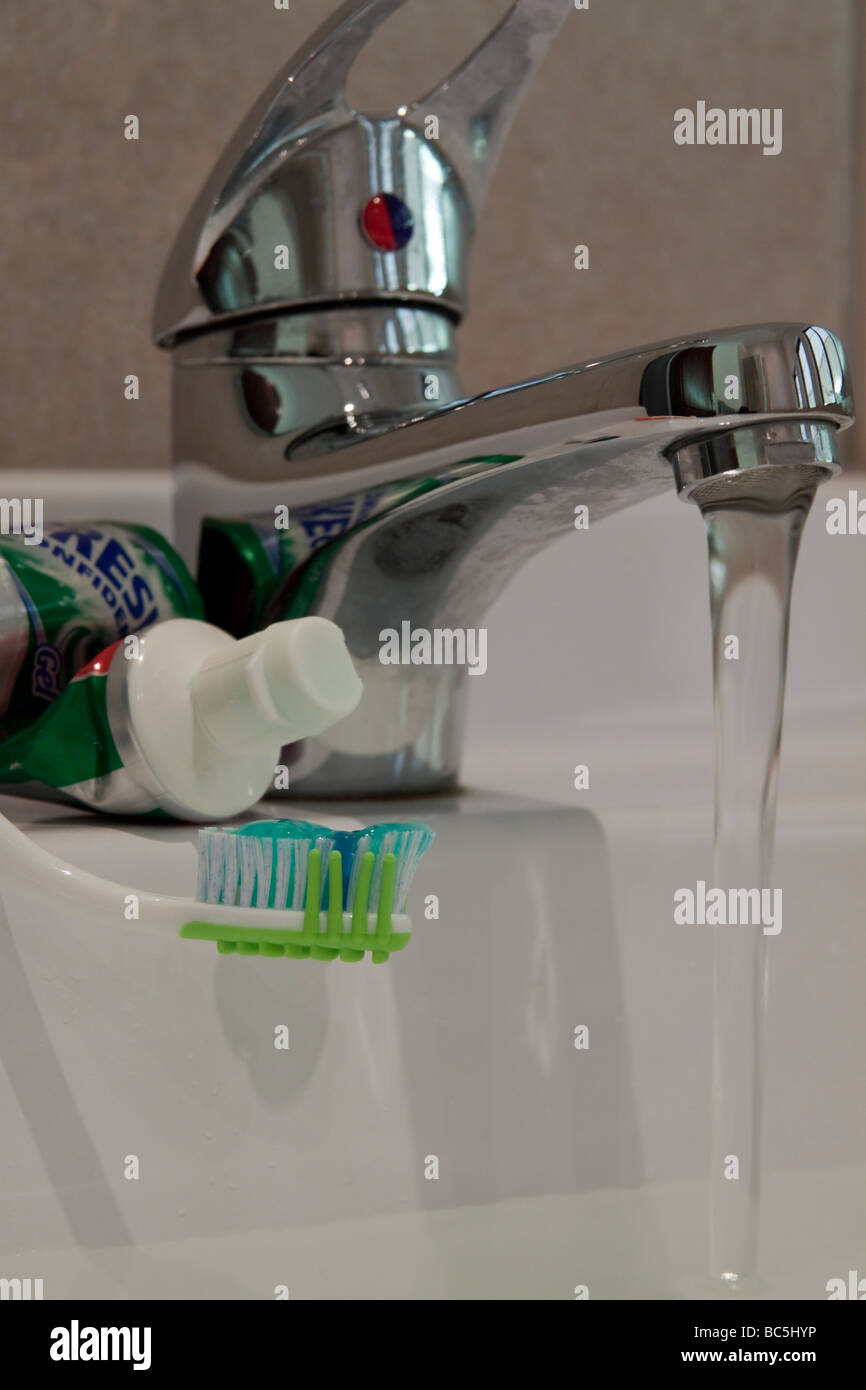Nahaufnahme von Zahnbürste und Einfügen mit Waschbecken Wasserhahn Stockfoto