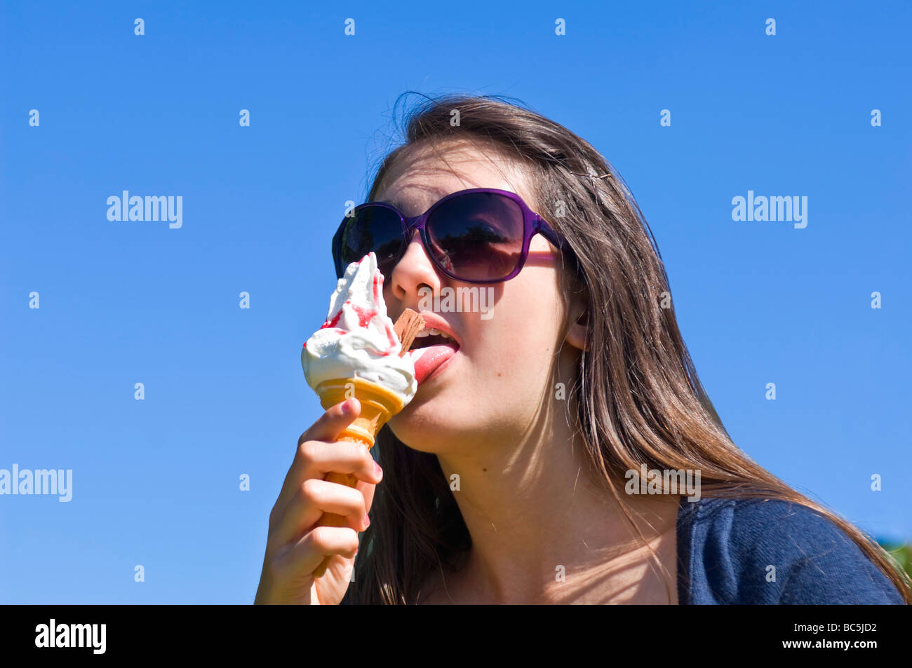Horizontale Porträt eines attraktiven Teenager Mädchen mit großen Sonnenbrillen ein 99 Eis essen, an einem sonnigen Tag Stockfoto