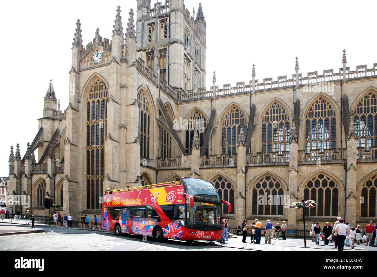 EINE MODERNE OFFENE TOP ROT TOUR-BUS VOR DER ALTEN ABTEIKIRCHE VON BATH IN SOMERSET, ENGLAND. Stockfoto