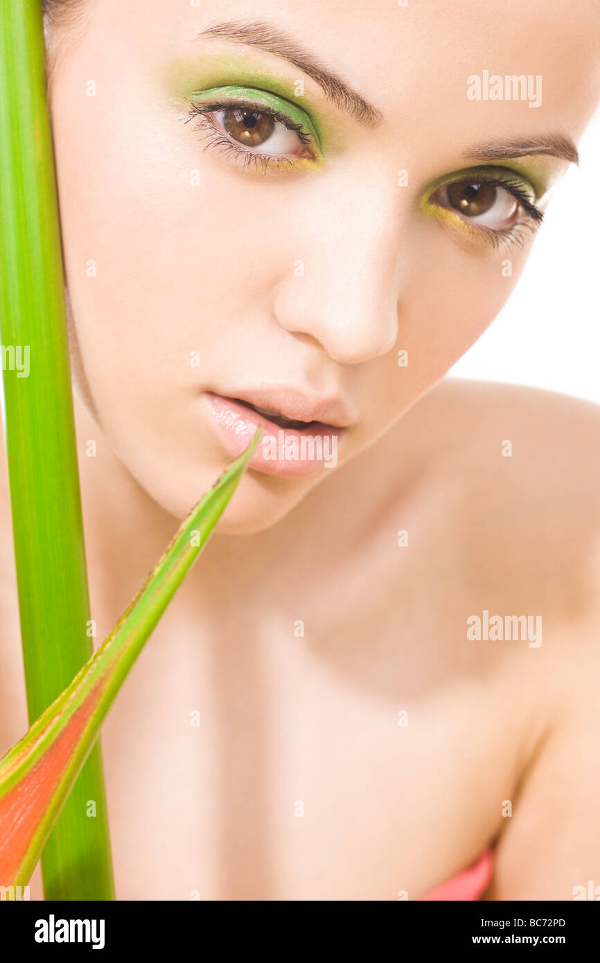 Frau mit grünem Make-up und Pflanze neben dem Gesicht Stockfoto