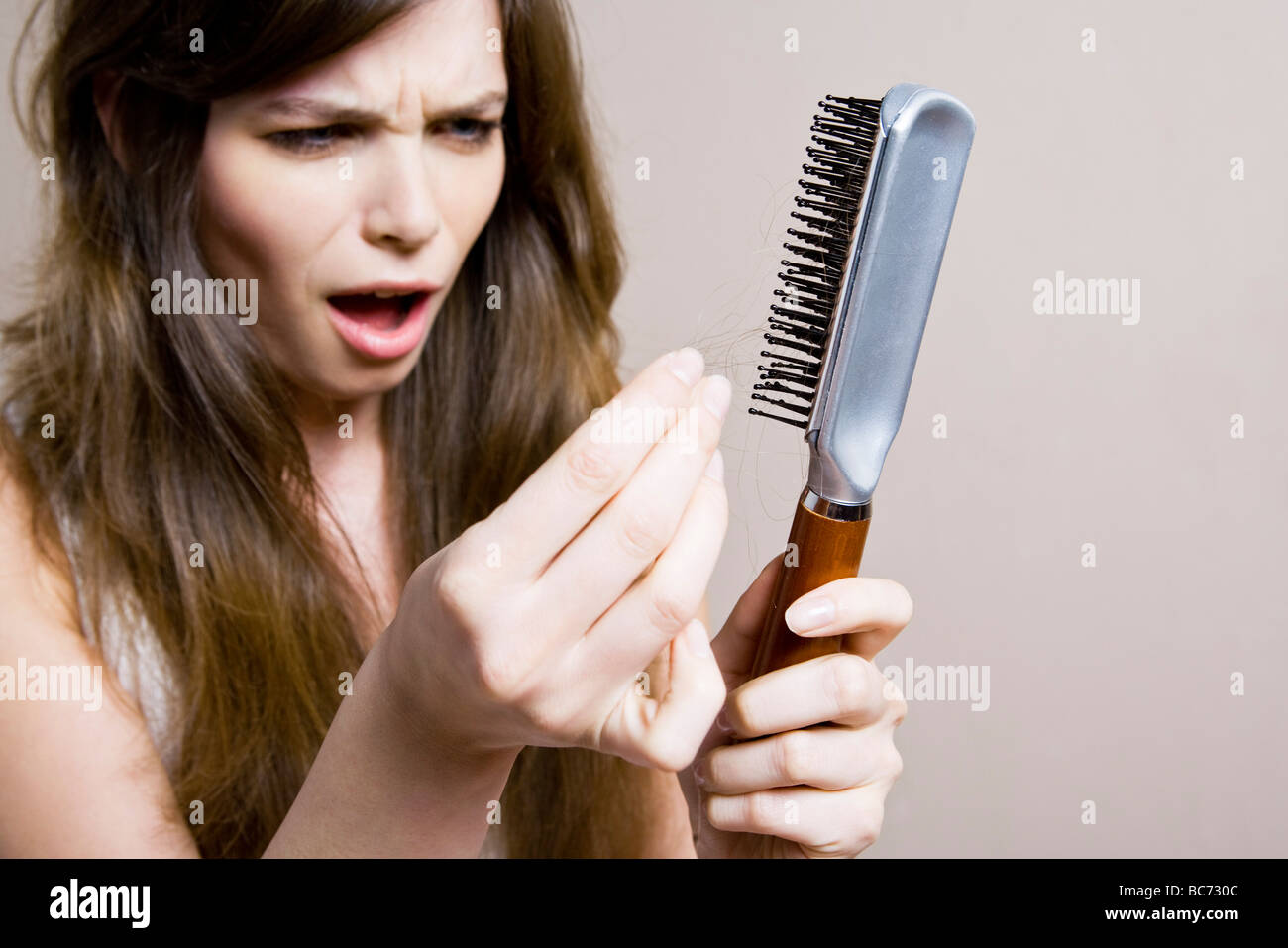 unzufriedene Frau mit Haarbürste Stockfoto