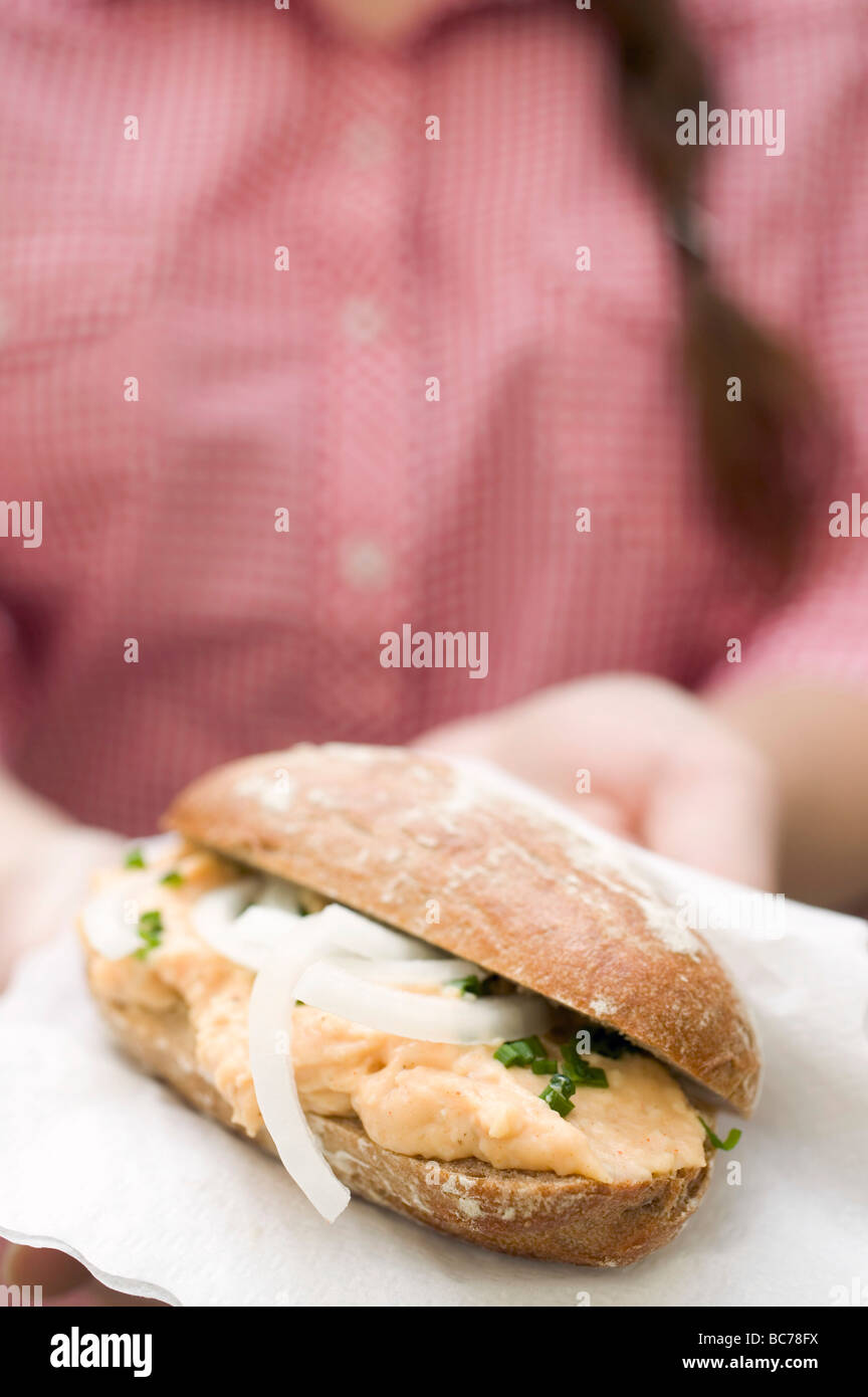 Frau Holding Brötchen mit Obatzda (Camembert Ausbreitung) & Zwiebeln- Stockfoto