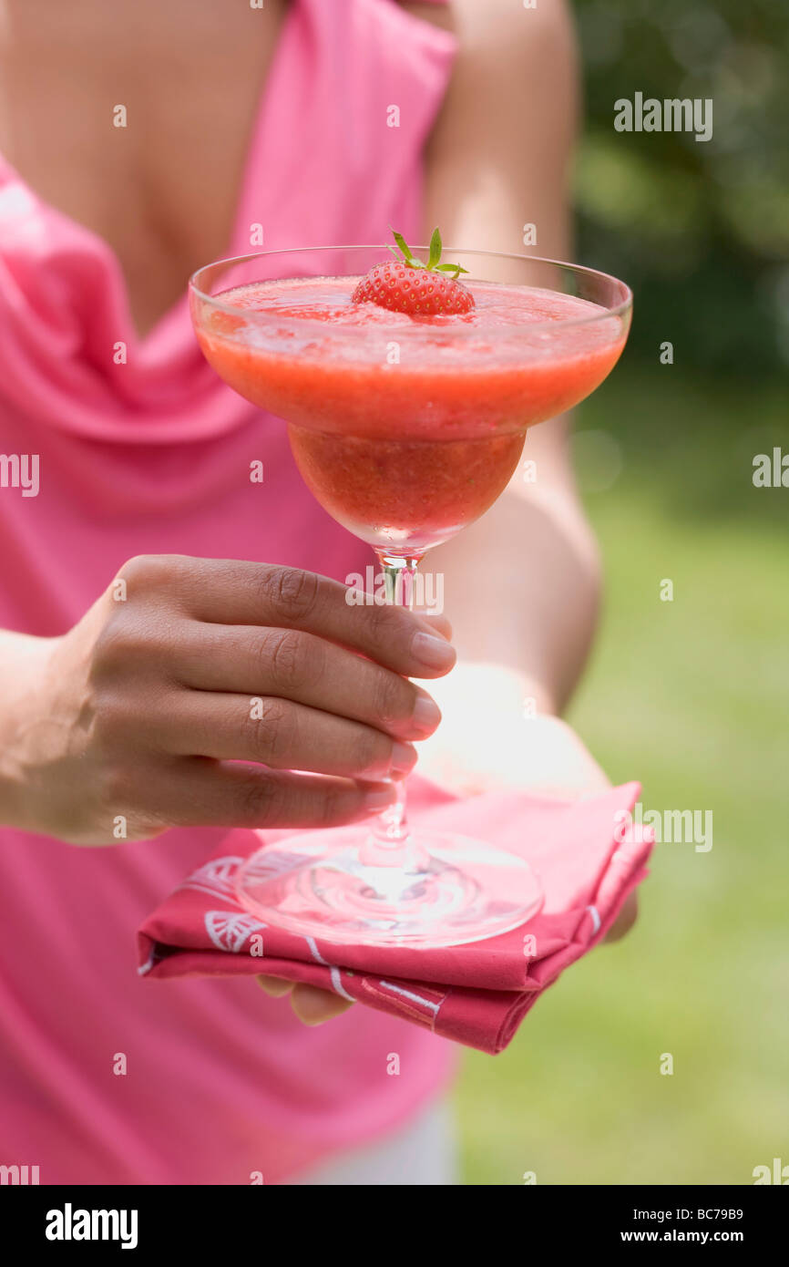Frau Holding fruchtigen Erdbeer Drink aus Türen heraus- Stockfoto