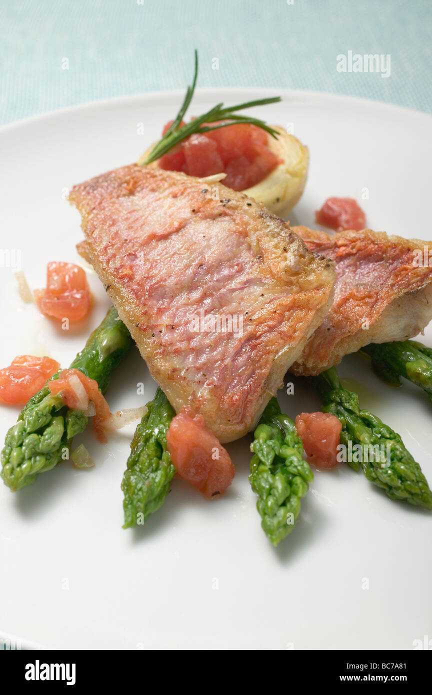 Gebratene Rotbarbe Filets mit Spargel und Tomaten- Stockfoto
