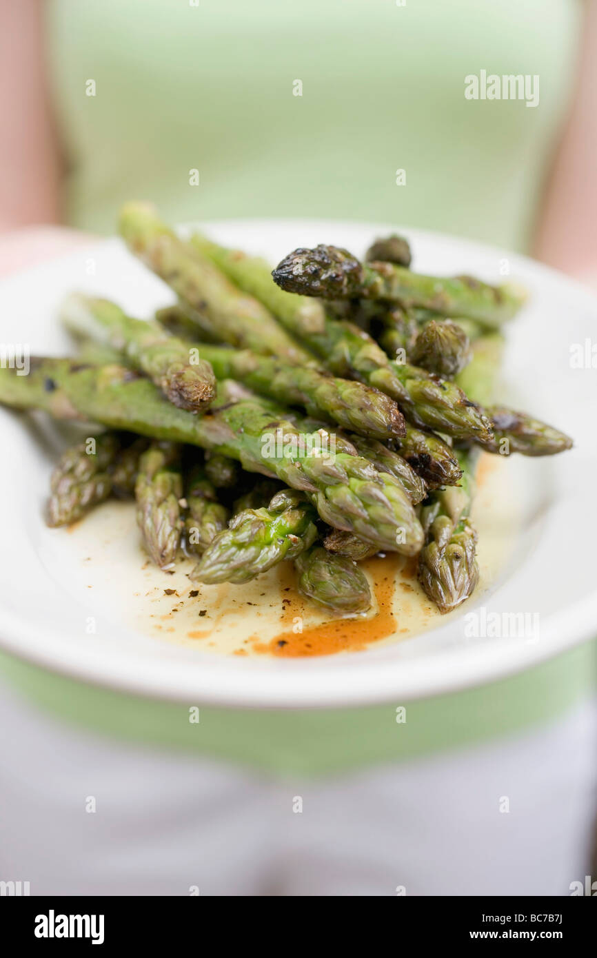 Frau mit einem Teller mit gegrilltem grünem Spargel- Stockfoto