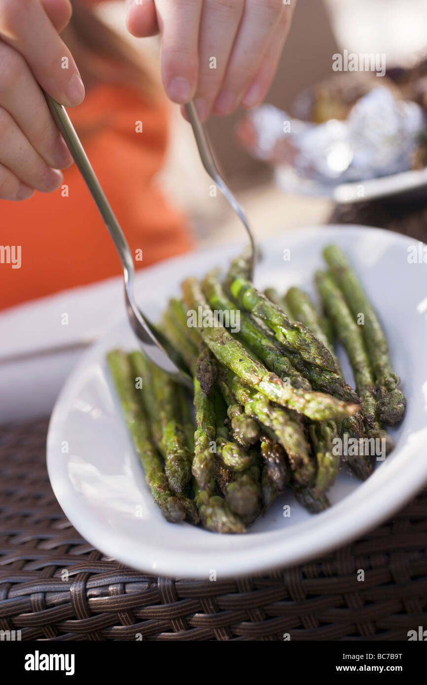 Person, die gegrillten Spargel aus einem Teller- Stockfoto