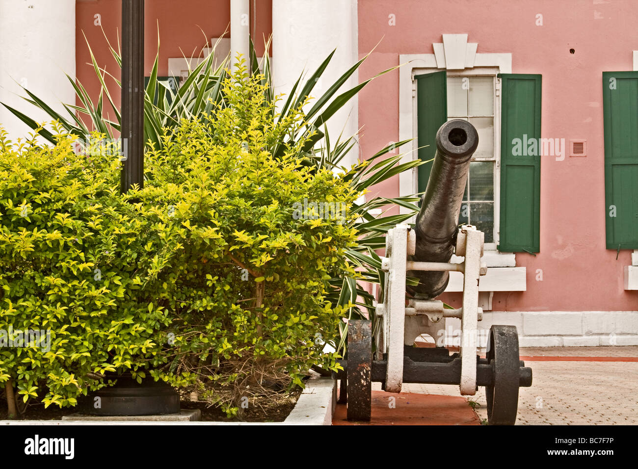 Replik einer Kanone von einem Busch in front das bahamaische Parlamentsgebäude in Nassau, Bahamas Stockfoto