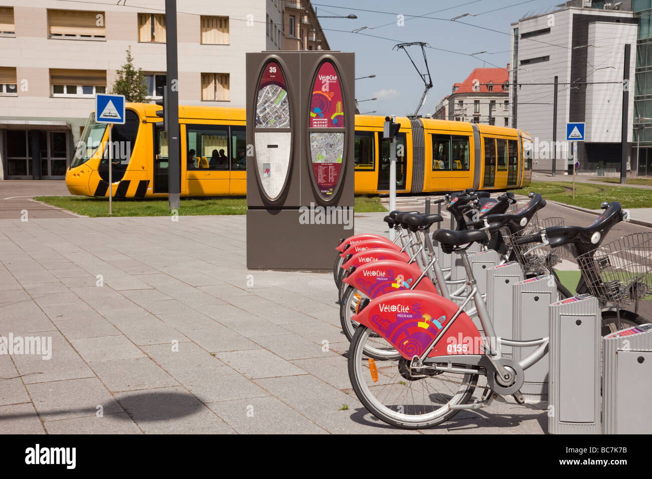 Mulhouse Elsass Frankreich Europa Geschwindigkeit e-Bikes zu vermieten in der Straßenbahnstation mit gelben Tram Zug auf s-Bahn-Netz Stockfoto