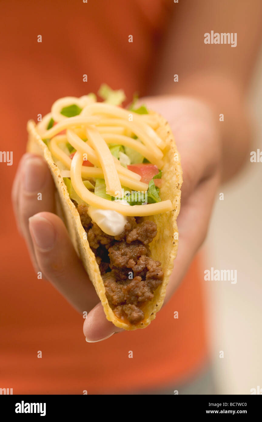 Hand, die einen Taco gefüllt mit Hackfleisch und Käse - Stockfoto