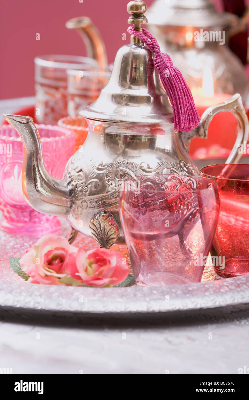 Silberne Teekanne, Gläser, Rosen und Windlichter auf Tablett- Stockfoto