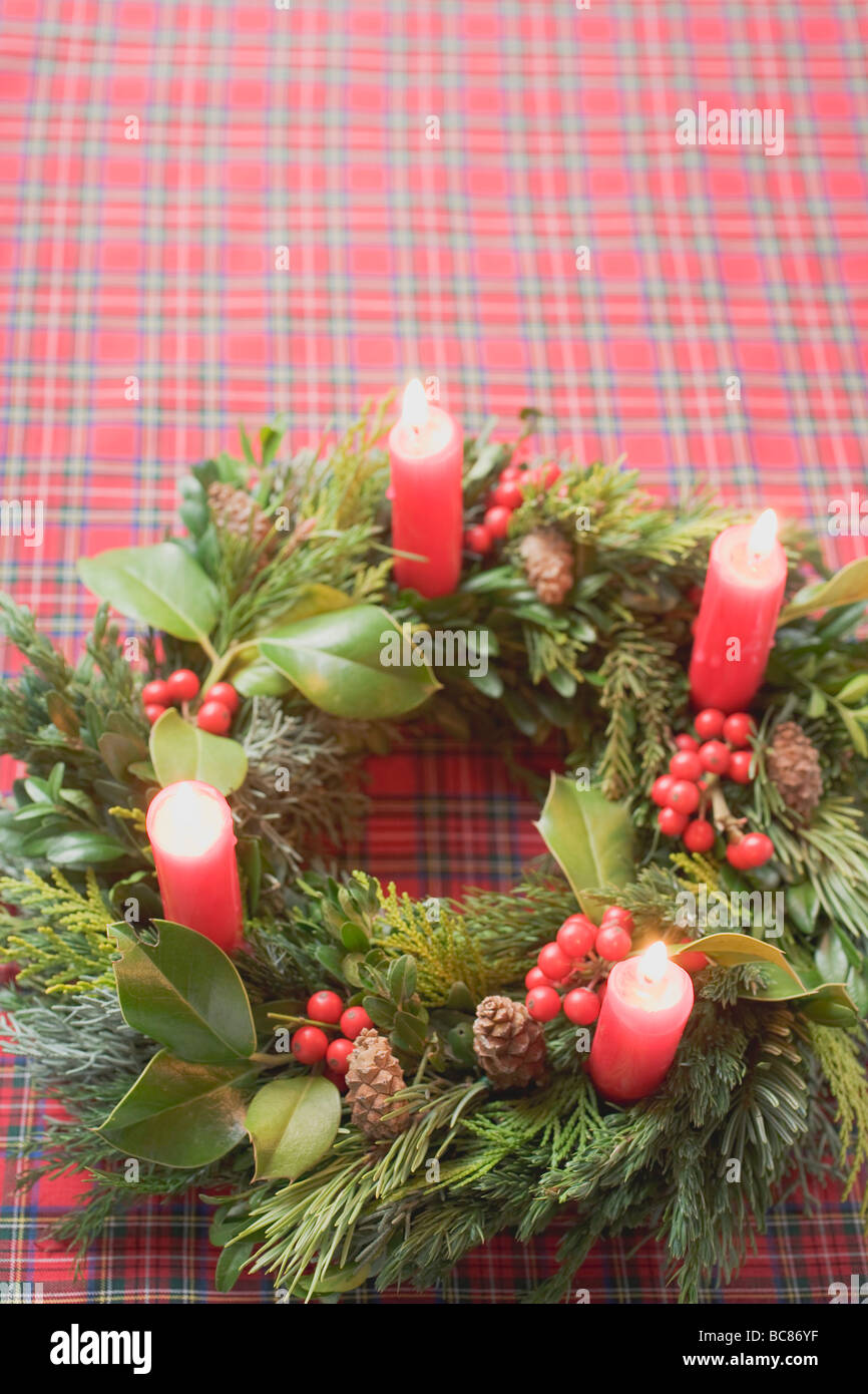 Adventskranz mit vier brennenden Kerzen auf aufgegebenes Tuch- Stockfoto