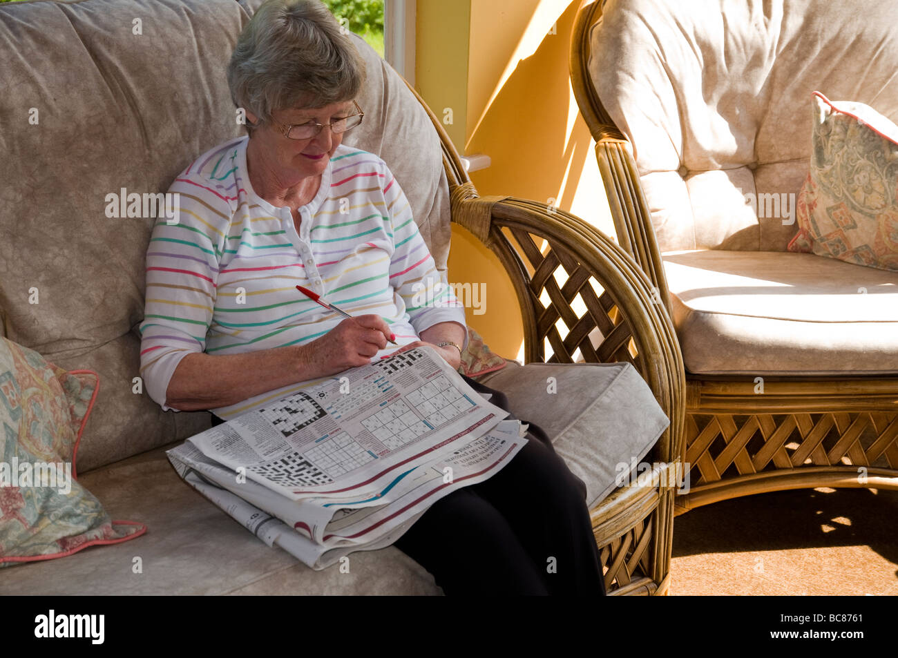 Eine Frau, die Rätsel in einer Tageszeitung. Stockfoto