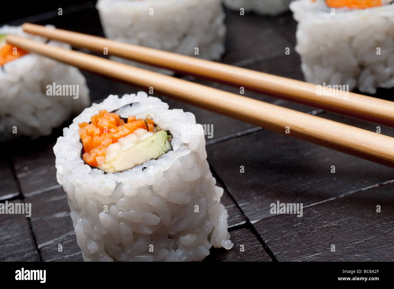 eine geneigte horizontale flachen Fokus Makro Sushi mit Copsticks auf einem schwarzen Hintergrund aus Holz Stockfoto