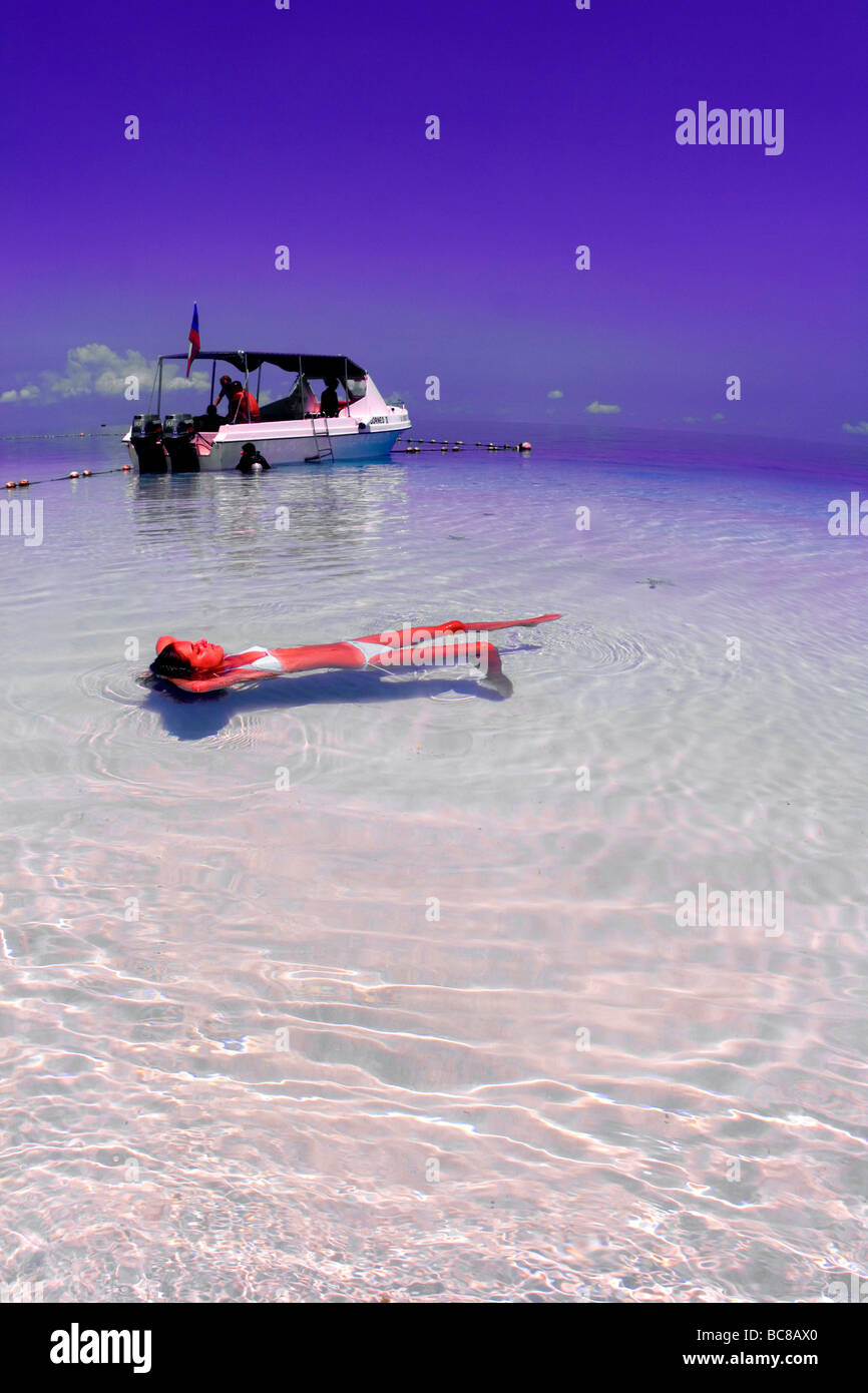 Mädchen in weißen Bikini im seichten Wasser über einem weißen Sand zu schweben. Tauchboot und Chocolate Chip Seestern, Protoreaster nodosus Stockfoto