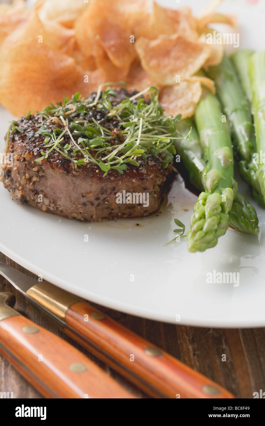 Gepfefferter Steak mit Kresse, grüner Spargel & Kartoffelchips- Stockfoto
