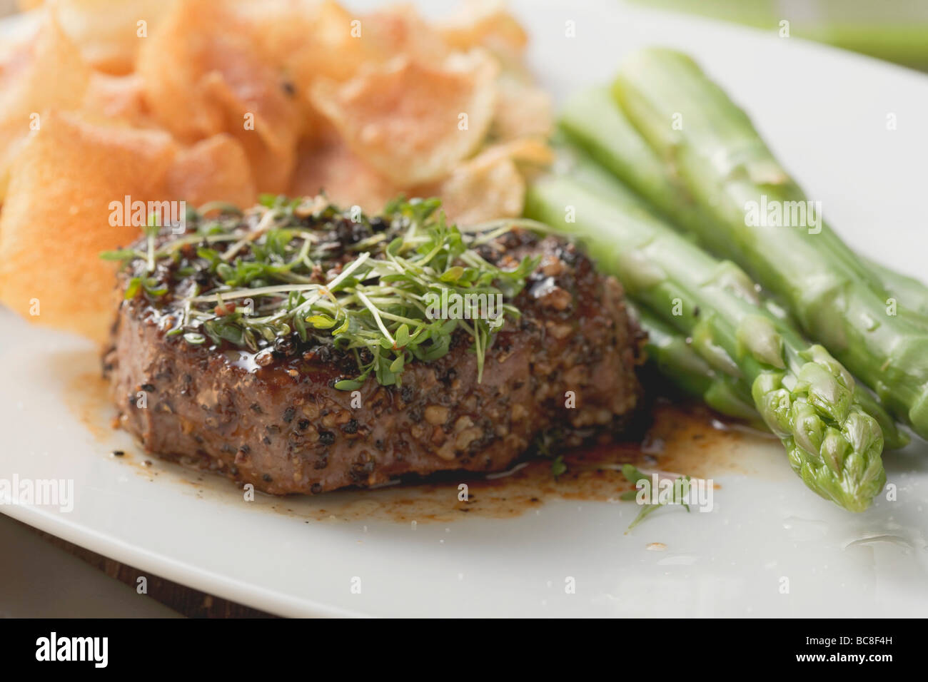 Gepfefferter Steak mit Kresse, grüner Spargel & Kartoffelchips- Stockfoto