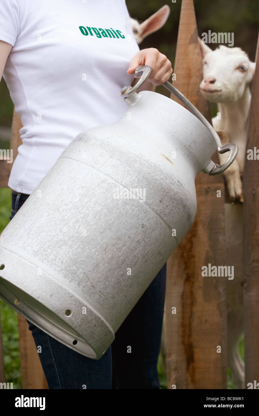 Frau mit Milch kann vor Ziege stand- Stockfoto