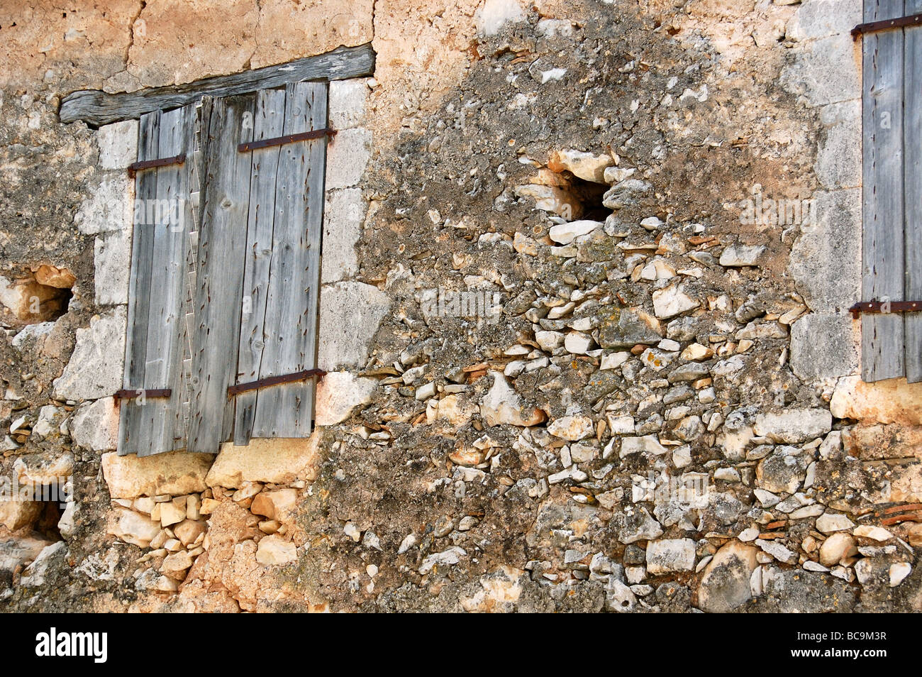 Verlassenes Haus von außen. Steinmauer und verwitterte Fenster Rollladen Detail. Stockfoto