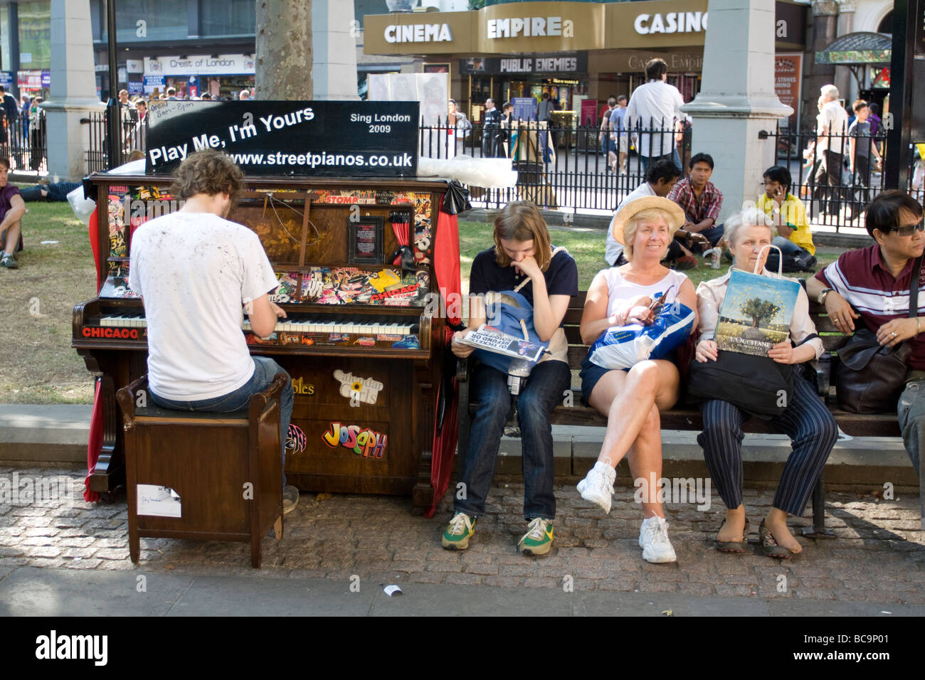 Man spielt Klavier neben Touristen - Leicester Square - London Stockfoto