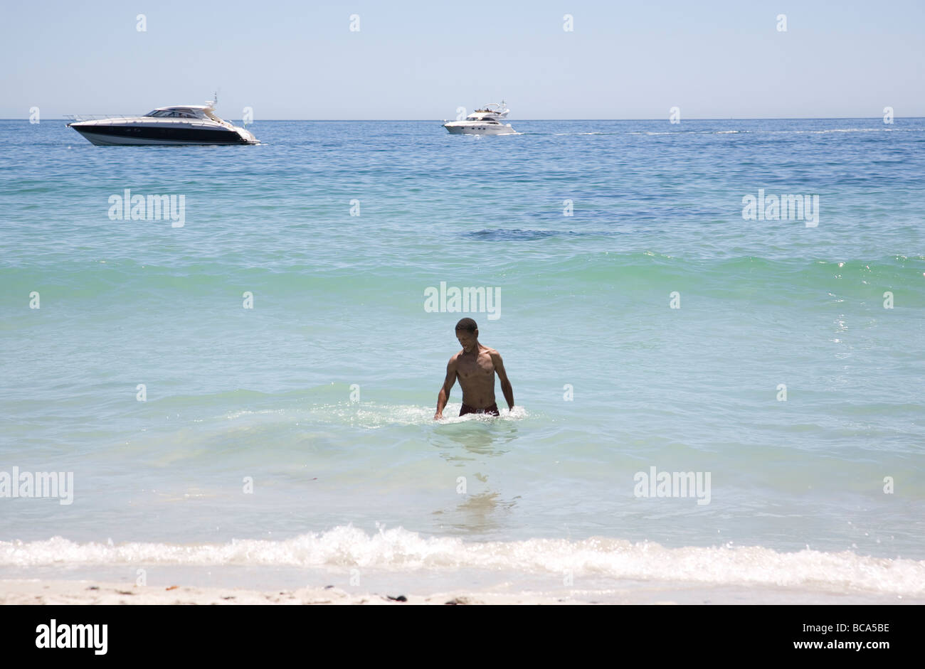 Schwarzer Rüde Schwimmen im Ozean mit Yachten. Stockfoto