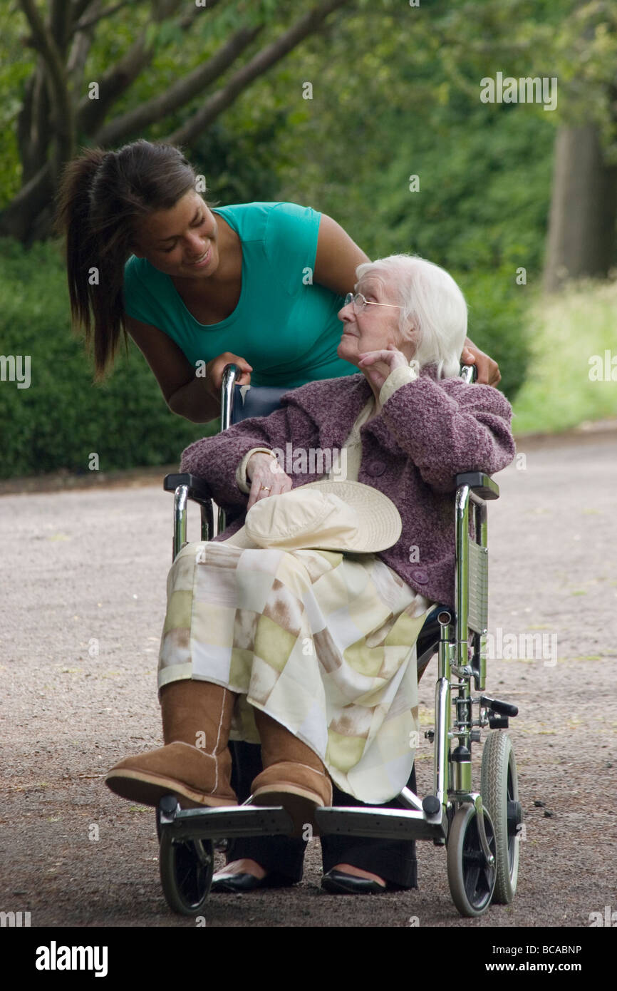 junge Frau, die ältere Dame im Rollstuhl schieben Stockfoto