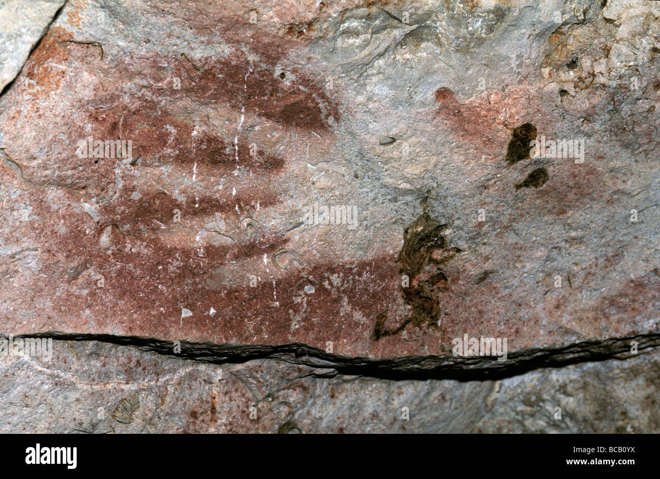 Uralte Aboriginal Kunst ockerfarbenen Felsmalereien eine Hand an der Höhlenwand. Stockfoto