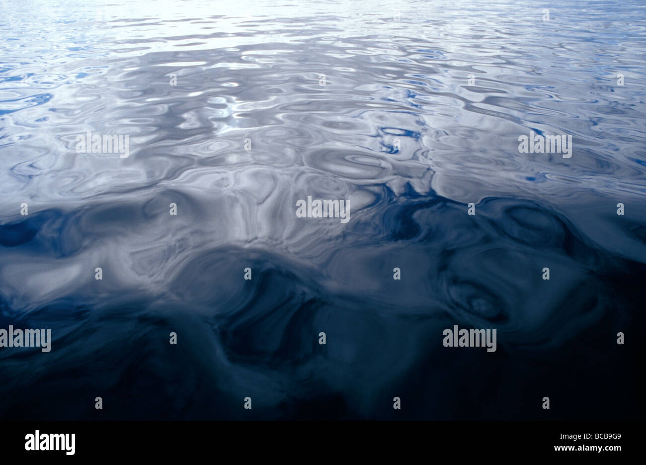 Ein sehr ruhiges Meer spiegelt grau-blauen Wolken schweben in Richtung Küste Stockfoto