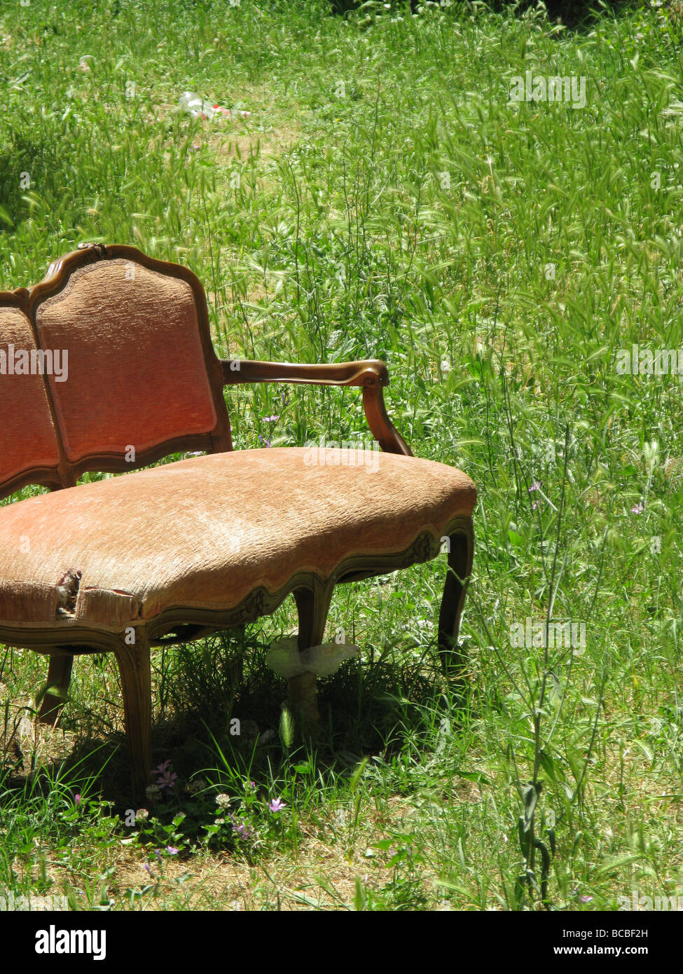 eine alte beschädigte Sofa in Feld auf Land entsorgt Stockfoto