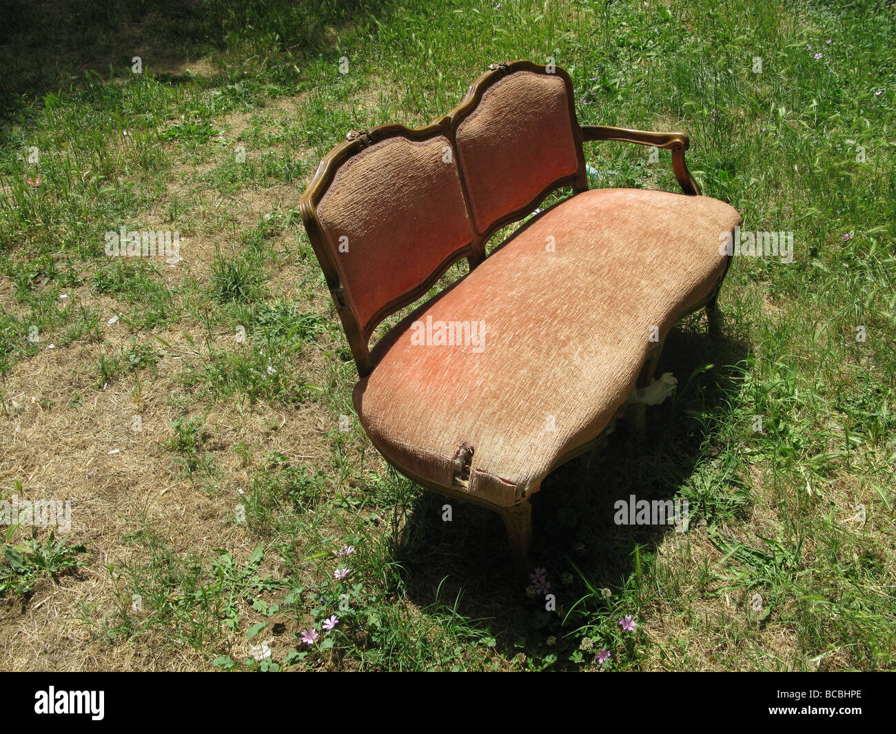 eine alte beschädigte Sofa in Feld auf Land entsorgt Stockfoto